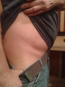 A person lifts their shirt to reveal their bare side and hip, perhaps in a moment of vulnerability shaped by trauma. One...
