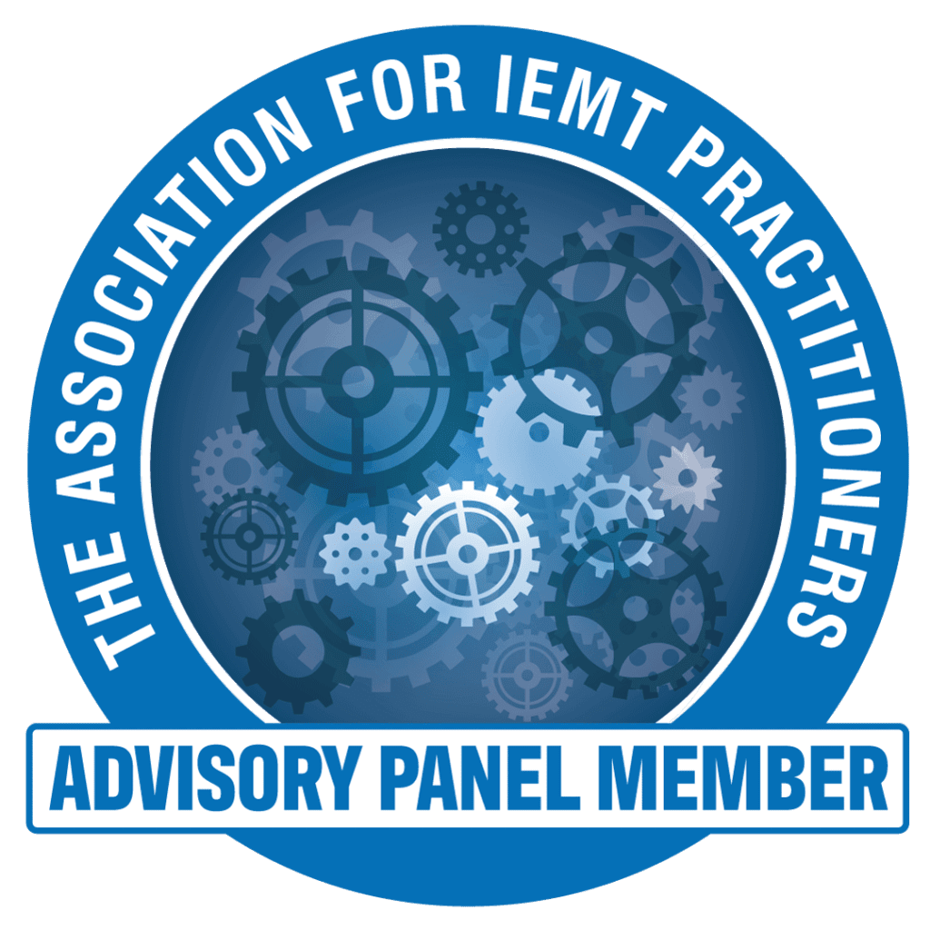 A blue circular badge with gears in the centre and the text “THE ASSOCIATION FOR IEMT PRACTITIONERS” around the edge. At...