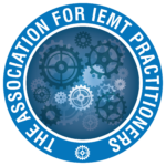 A blue circular logo with The Association for IEMT Practitioners in white text around gears of various sizes in the centre. A small white gear is also at the bottom of the circle.